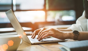 Hands typing on a laptop