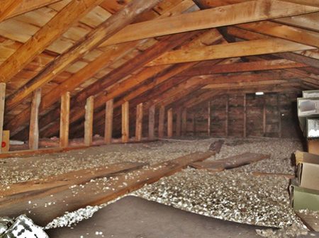 An attic built with black spruce wood was photographed in Ontario, Canada. Vermiculite insulation and stored boxes show in the image.