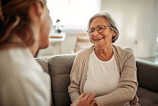 elderly woman smiling while receiving support from her doctor