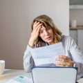 Stressed middle-aged woman looking at bills